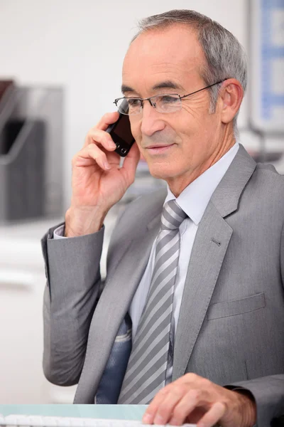65 år gammal man klädd i en grå kostym och ringer — Stockfoto