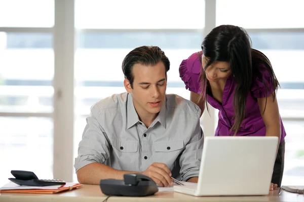 Par på ett skrivbord med en bärbar dator — Stockfoto