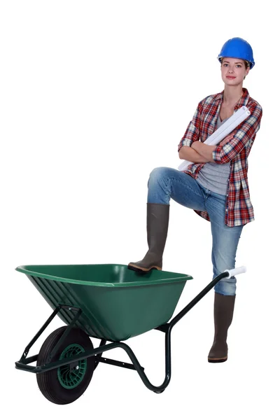 Tradeswoman con il piede appoggiato su una carriola — Foto Stock