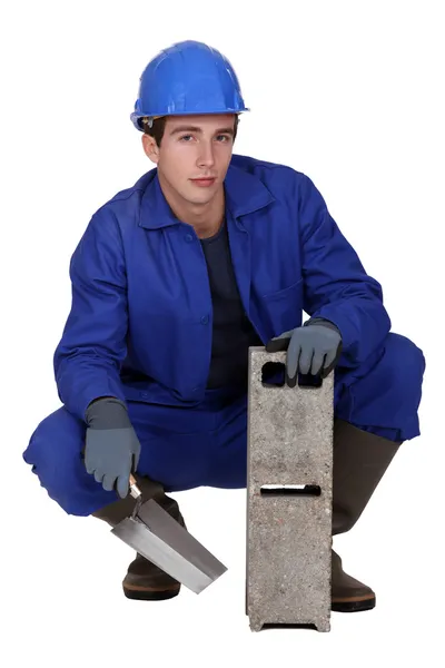 Trabajador sosteniendo un bloque de cemento y una paleta —  Fotos de Stock