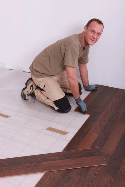 Homem que estabelece piso de madeira — Fotografia de Stock