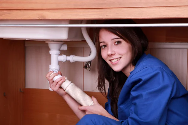 Jovem mulher encaixando o tubo de resíduos em uma pia da cozinha — Fotografia de Stock