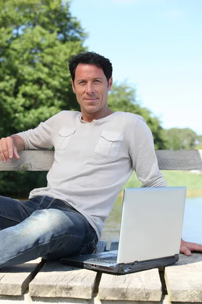 Homme assis sur le banc du parc avec ordinateur portable — Photo