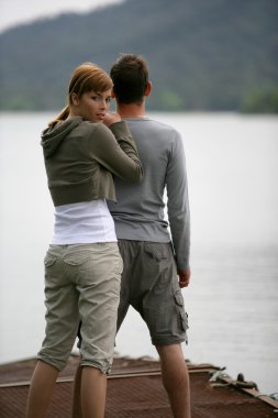 Couple stood by peaceful lake clipart