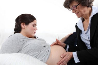 Doctor feeling a woman's pregnant stomach clipart