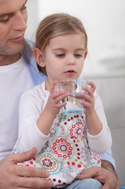 Father giving his daughter a glass of water to drink clipart