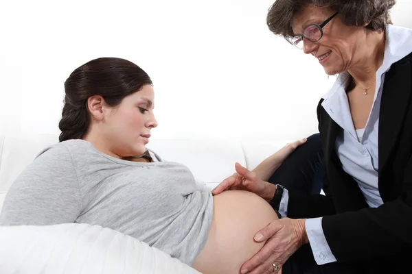 Läkaren känner en kvinna gravid mage — Stockfoto