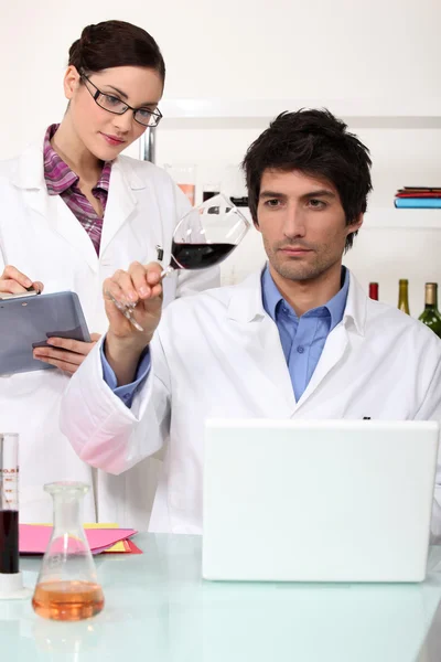 Homem e mulher testando vinho em laboratório — Fotografia de Stock