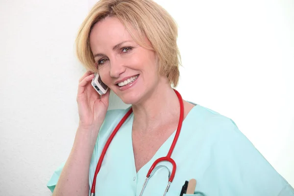 Female nurse speaking on mobile telephone — Stock Photo, Image