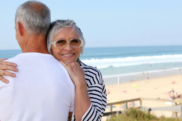 海の近くの彼女の夫を抱き締める年配の女性 — ストック写真