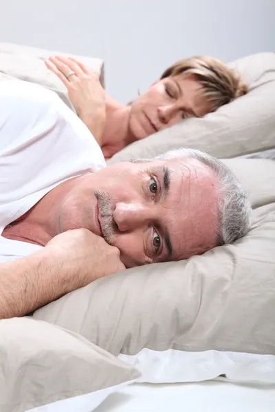 En man är vaken när hustrun sover — Stockfoto