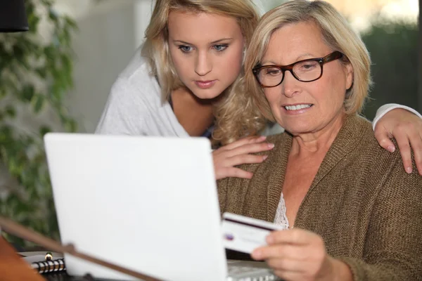 Äldre kvinna och ung flicka framför en laptop — Stockfoto