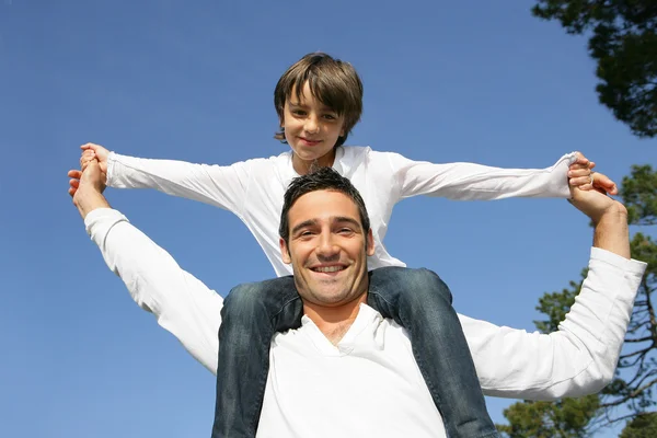 Kind rijden op zijn vaders schouders — Stockfoto