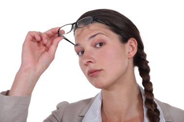 Curious brunette lifting her eyeglasses clipart