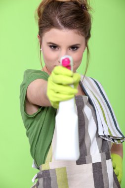 Girl holding detergent with pistol pump against green background clipart