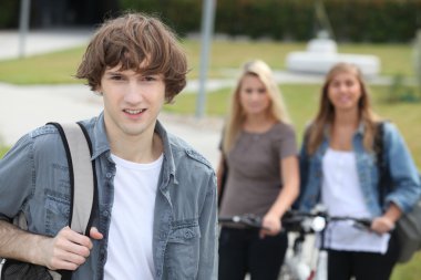 Young man standing in front of two girls with bikes clipart