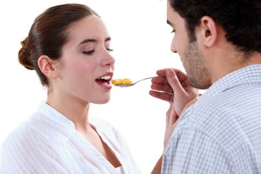 Boyfriend feeding his girlfriend with a spoon clipart