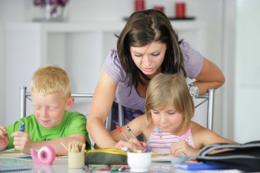 Mother helping her kids with the homework clipart