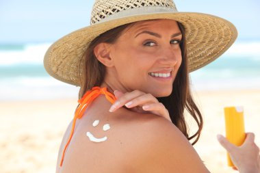 Woman applying suncream at the beach clipart