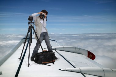 Photographer flying on a plane wing clipart