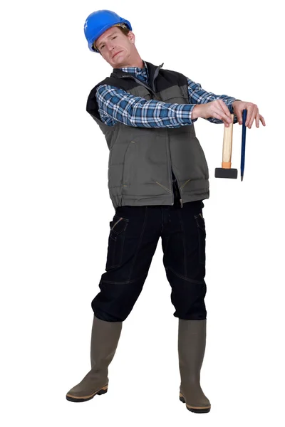 Ambachtsman holding een hamer en een wig en op zoek walgen — Stockfoto