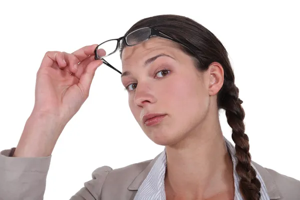 Zvědavý bruneta zvedání brýlím — Stock fotografie
