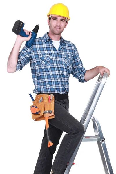 Řemeslník vylézt na žebřík a drží vrtačku — Stock fotografie