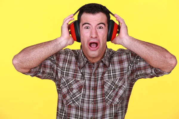 Craftsman wearing headphones can't stand the noise — Stock Photo, Image
