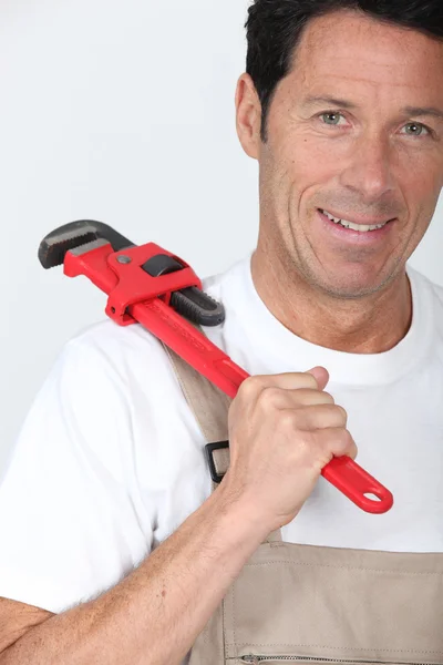 Handyman com uma chave vermelha grande em seu ombro — Fotografia de Stock