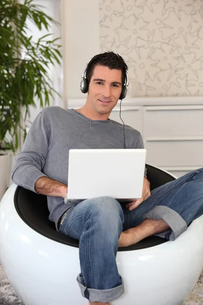Uomo sorridente con laptop e auricolare — Foto Stock