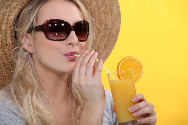 Жінка п'є скляний апельсиновий сік — стокове фото