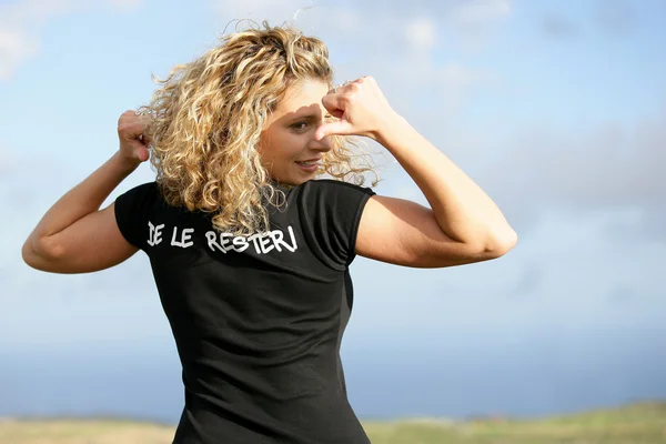 Блондинка в поле указывает на футболку — стоковое фото