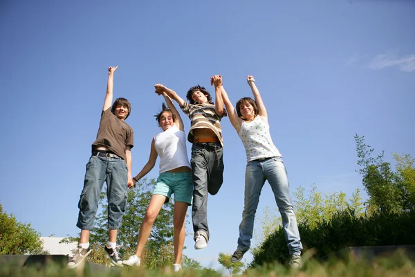 Gruppo di adolescenti che si tengono per mano e saltano in aria — Foto Stock