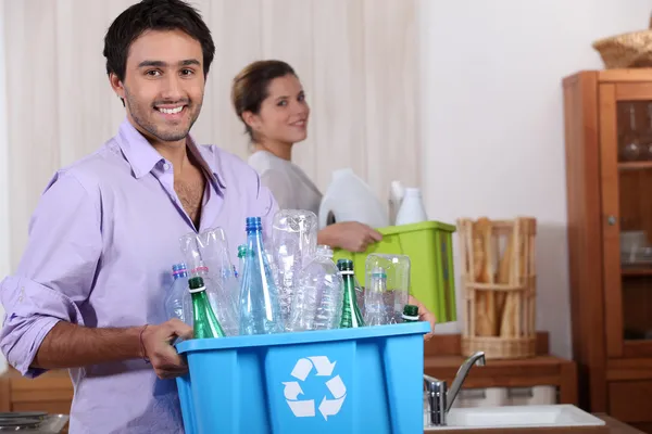 Um jovem casal reciclando plástico em sua cozinha — Fotografia de Stock