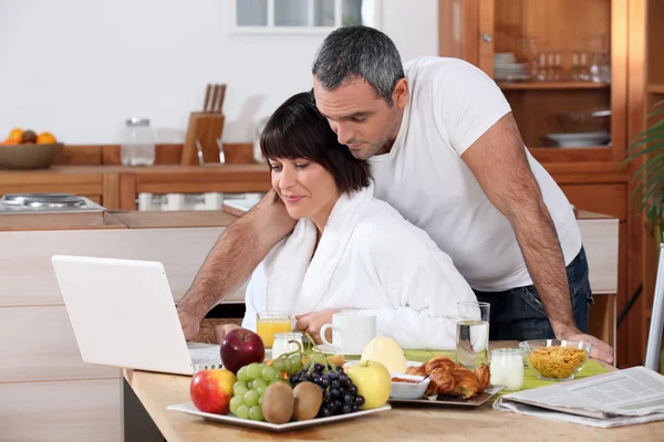 Casal olhando para o laptop durante o café da manhã — Fotografia de Stock
