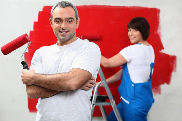Ζευγάρι βάψιμο εσωτερικών τοίχων σε κόκκινο — Φωτογραφία Αρχείου
