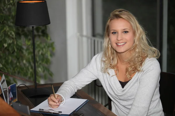 Jonge blonde vrouw schrijven op Klembord — Stockfoto
