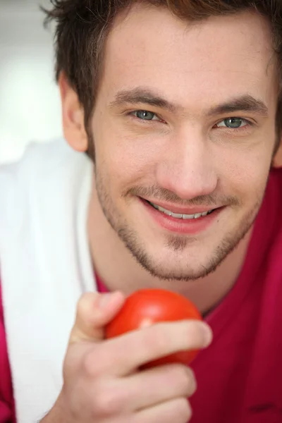 Jonge man met een tomaat — Stockfoto