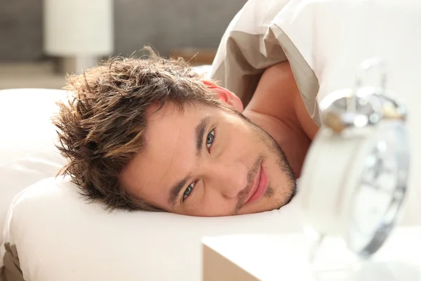 Junger Mann wacht im Bett auf — Stockfoto