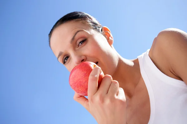 Brunetka gryzący w czerwone jabłko — Zdjęcie stockowe