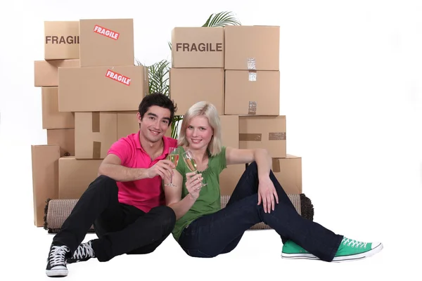 Couple drinking champagne amid packing boxes — Stock Photo, Image