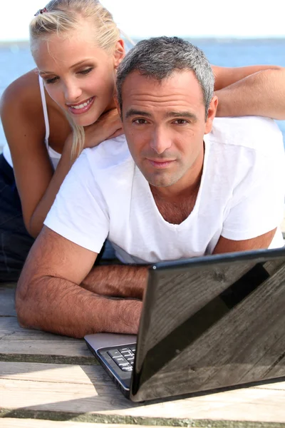 Couple with laptop on jetty — Stock Photo, Image