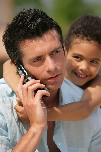 Homme au téléphone avec petit garçon métis — Photo
