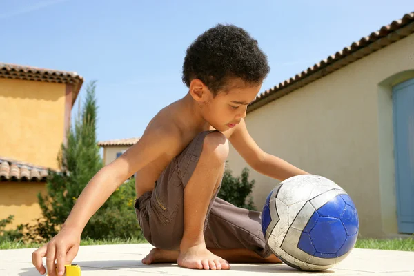 Маленький хлопчик сидить з м'ячем — стокове фото