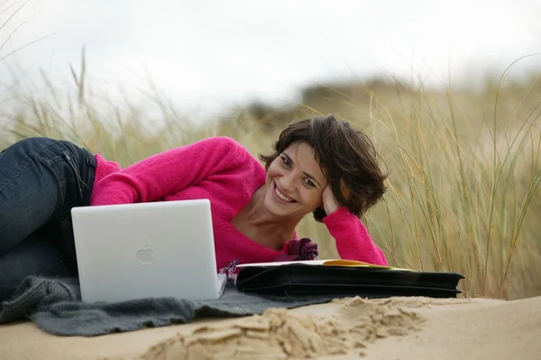 Egy nő használja a laptopját a parton. — Stock Fotó