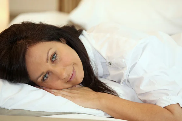 Vrouw liggend op een witte bed — Stockfoto