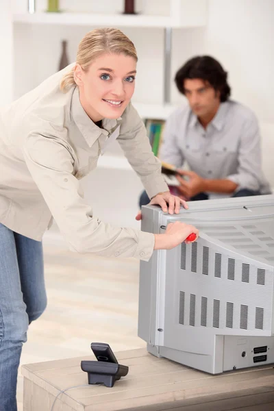 Woman removing the back of a tv set — Stock Photo, Image