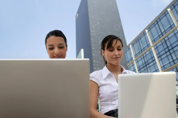 Zwei junge Geschäftsfrauen arbeiten an ihren Laptops — Stockfoto
