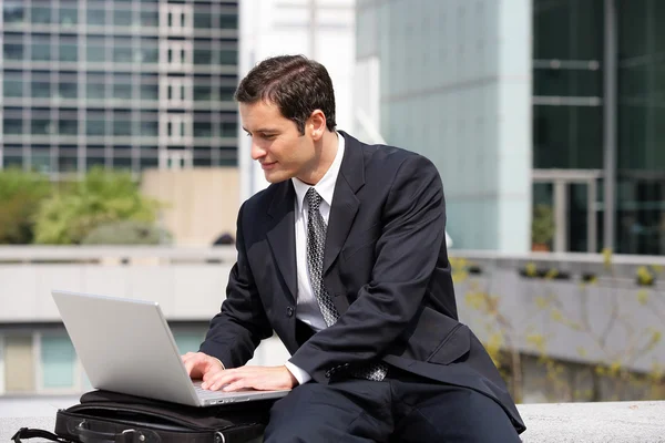 Uomo d'affari seduto con il computer portatile in città — Foto Stock