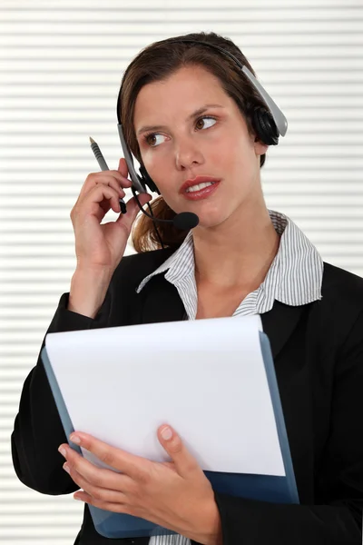 Vrouw luisteren naar een oproep op haar headset — Stockfoto